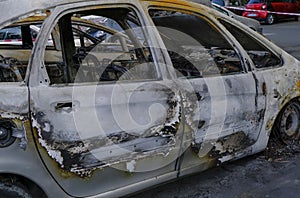 Burnt car`s door in the street close-up. Riot, civil protest, hooliganism, criminal in the city. Explosion, fire result. Car insur