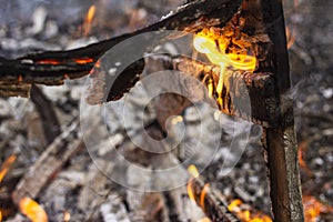 Burnt fence close-up on the ashes of a large fire, on a blurred background with a bokeh effect