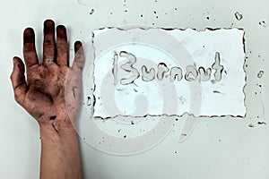 A burnt hand and white paper with burnout word. Work life balance, work stress and burnout concept