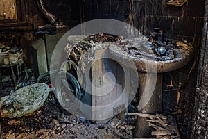 Burnt house interior. Burned burnt bathroom, Fused remains of furniture and washing machine