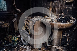 Burnt house interior. Burned burnt bathroom, Fused remains of furniture and washing machine