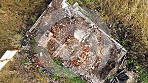 A burnt-out abandoned house with a protruding chimney, aerial view.