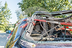 Burnt out car after a violent accident with police barrier tape in red and white with the German word for police barricade, German