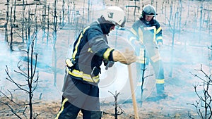 Burnt-out ground is getting damped down by the firemen