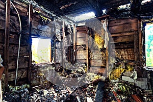 Burnt out house with charred roof trusses and burnt furniture