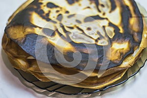 Burnt pancake in a plate on the table.