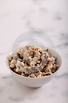 Burnt popcorn in the small white bowl on ceramic