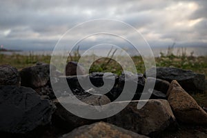 Burnt stones lie on the beach. Extinguished campfire