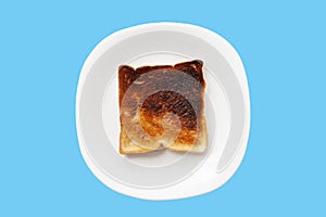 Burnt toast in white plate isolated on blue background.