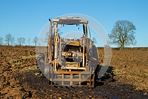 Burnt tractor digger in ploughed field
