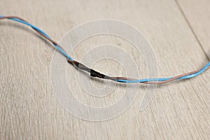 Burnt wires on wooden floor, closeup. Electrical short circuit