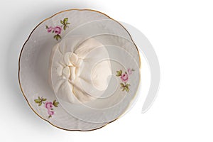 Burrata cheese on a porcelain saucer. Isolated on a white background