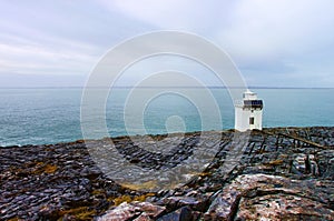 Burren lighthouse on the rocky coast of ireland.