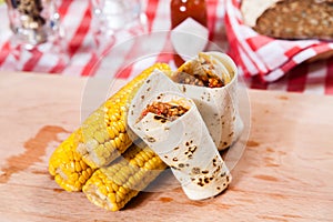 Burrito with corn on wooden board