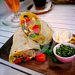 Burrito wraps with beef and vegetables on a wooden rectangular plate.  Beef burrito, Mexican food.