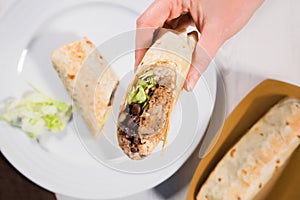 Burrito wraps with pulled pork, beans, rice and vegetables on white plate