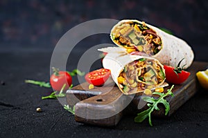 Burritos wraps with beef and vegetables on black background