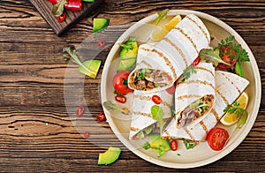 Burritos wraps with beef and vegetables on a wooden background