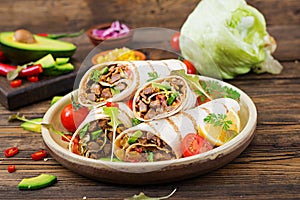 Burritos wraps with beef and vegetables on a wooden background