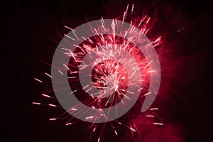 Burst of red fireworks at night - vibrant red streaks and sparks - smoke clouds - celebration, new years day, fourth of july,