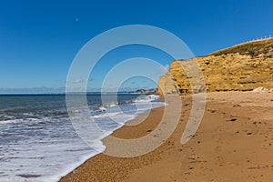 Burton Bradstock beach Dorset England UK Jurassic coast with sandstone cliffs and white waves in summer with blue sea and sky