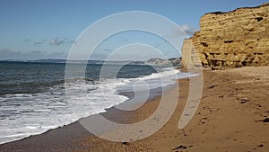 Burton Bradstock sandstone cliffs and waves crashing in to shore Dorset England uk