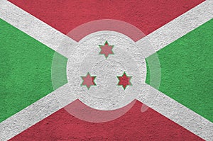 Burundi flag depicted in bright paint colors on old relief plastering wall. Textured banner on rough background