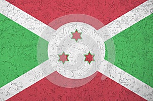 Burundi flag depicted in bright paint colors on old relief plastering wall. Textured banner on rough background