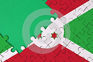 Burundi flag is depicted on a completed jigsaw puzzle with free green copy space on the left side