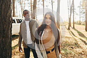 Bus is behind. Young couple is traveling in the forest at daytime together