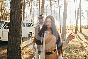 Bus is behind. Young couple is traveling in the forest at daytime together