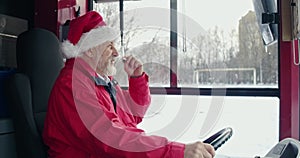 Bus driver in Christmas hat sitting, speaking in microphone.