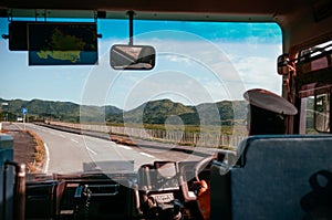 Bus driver is driving with hands on steering wheel on empty asphalt road