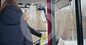 Bus driver looking forward, passengers greeting.