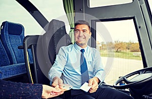 Bus driver with money selling ticket to passenger