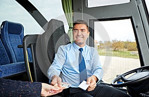 Bus driver with money selling ticket to passenger