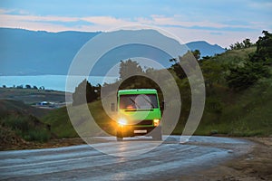 Bus goes along the road along the mountains