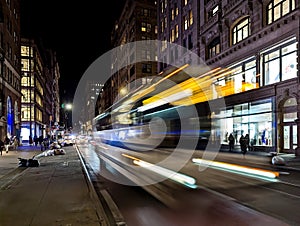 Bus headlights streaking down the street with motion blur effect at night in New York City