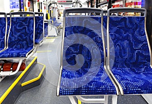 The bus inside. Interior of empty modern european city bus with blue seats and yellow hangers.