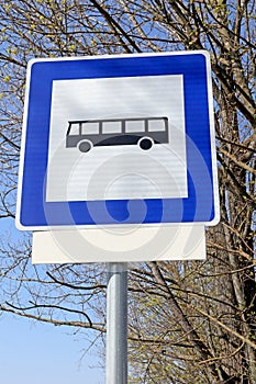 Bus stop road sign in front of a tree