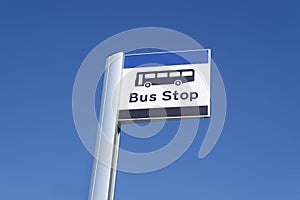 Bus stop sign sky background blue white clouds view below information public transport school old age pensioner travel free coach