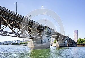 Buscle Burnside Bridge with big support columns and truss roadbed across Willamette River in Portland Oregon