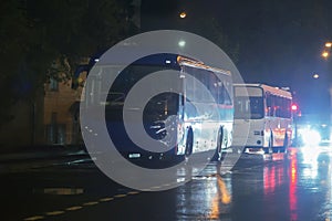 buses on the street at night in the rain