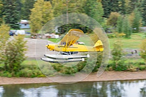 Bush float plane flying over river in Alaska