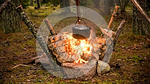 Bushcraft setting with a camping pot hanging over a burning fire.