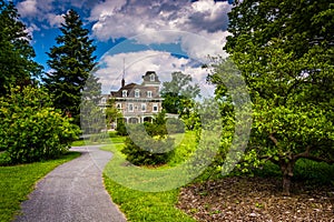 Bushes and trees along a path and the Cylburn Mansion at Cylburn Arboretum, Baltimore, Maryland.