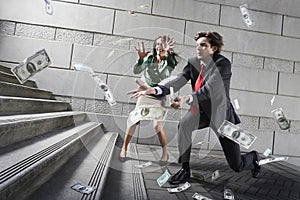 Busines man and woman collecting falling money on steps