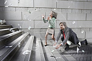 Busines man and woman collecting falling money on steps