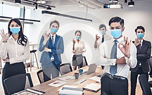 Busines people wearing face mask and showing ok gesture . Business meeting in modern office while pandemic of virus photo