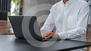 Businesman typing on laptop keyboard, wearing white shirt